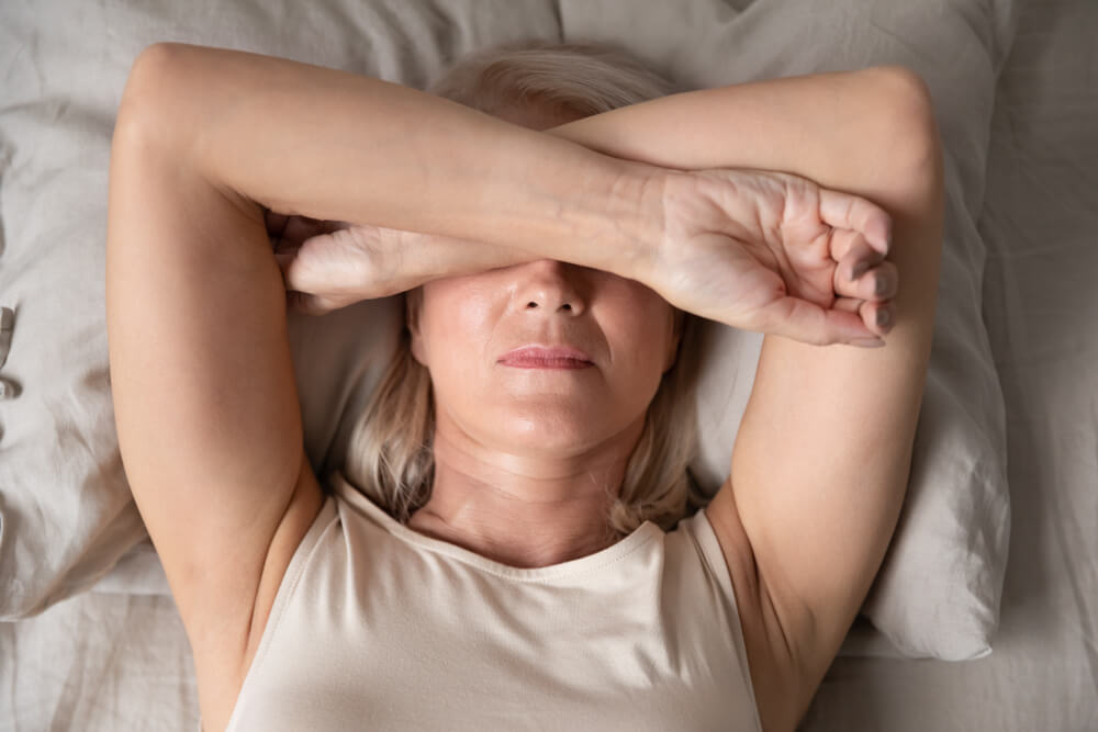 woman with arms over face, having trouble sleeping