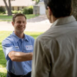 Two men shaking hands outside a house.