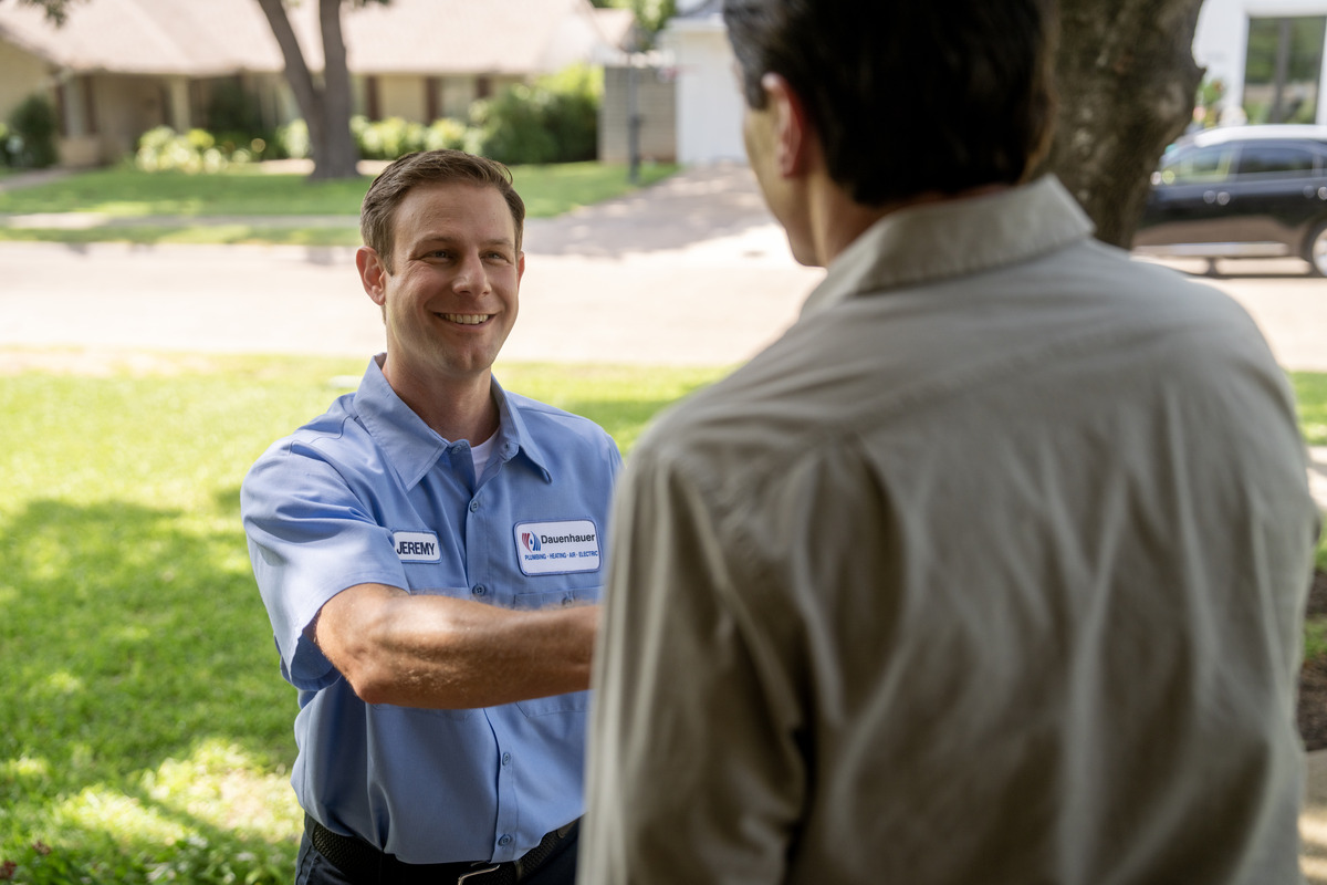 Two men shaking hands outside a house.